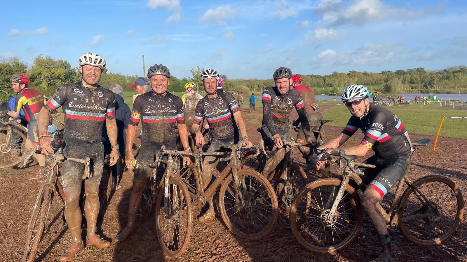 Did someone say mud-life crisis? 4 very muddy men posing with their bikes at the finish