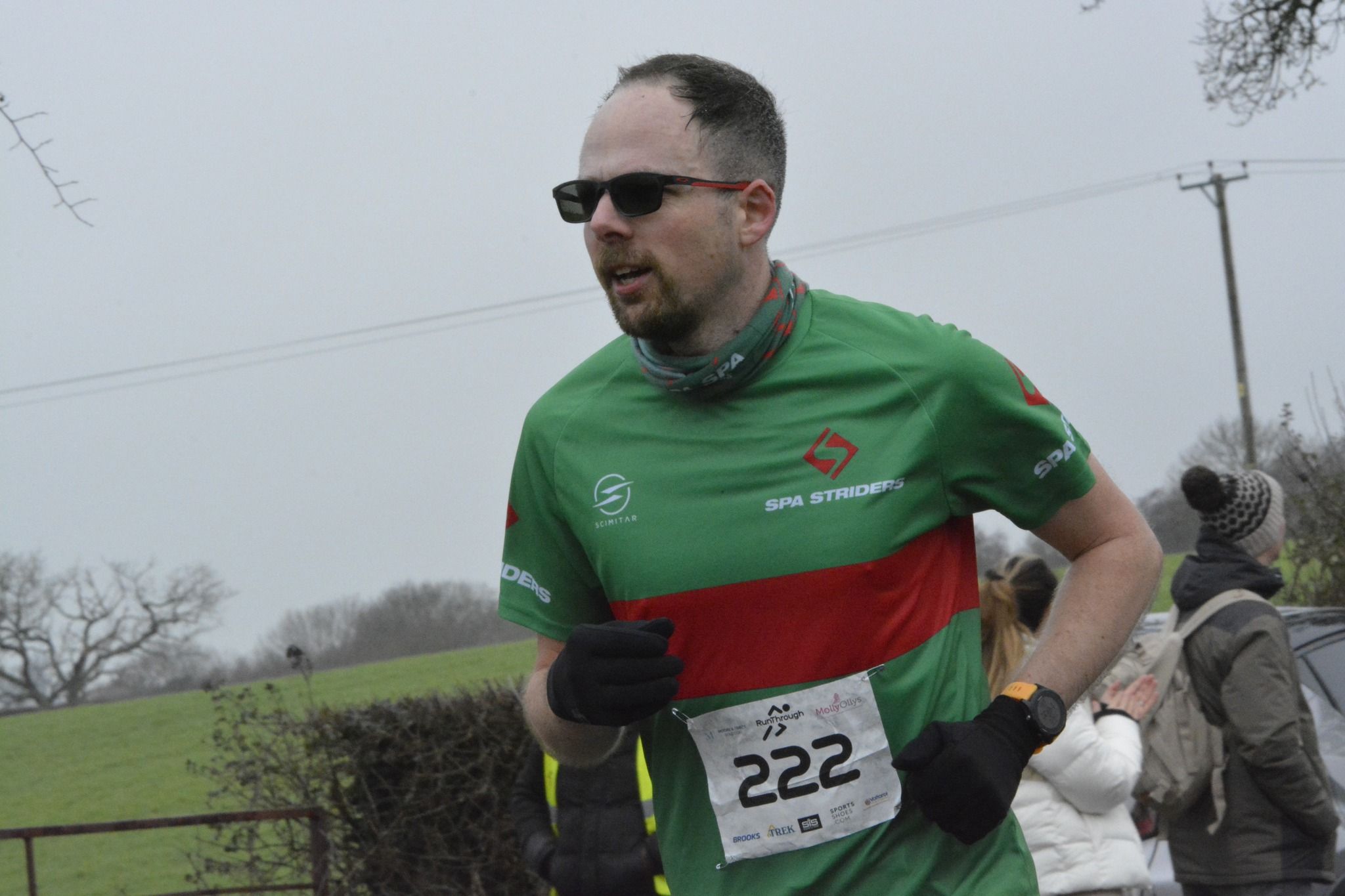 man in a green running top with a red stripe running